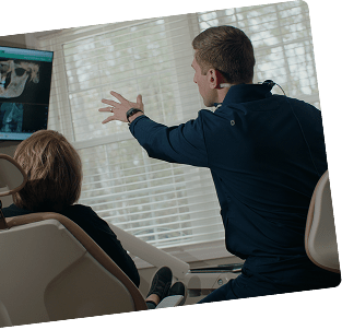 Dentist reviewing digital dental scans with a patient in a clinical setting.