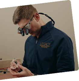 High-tech prosthetic dentistry in action: Specialist at Legacy Prosthodontics uses dental loupes for the ultra-precise adjustments needed for custom crown or denture models.